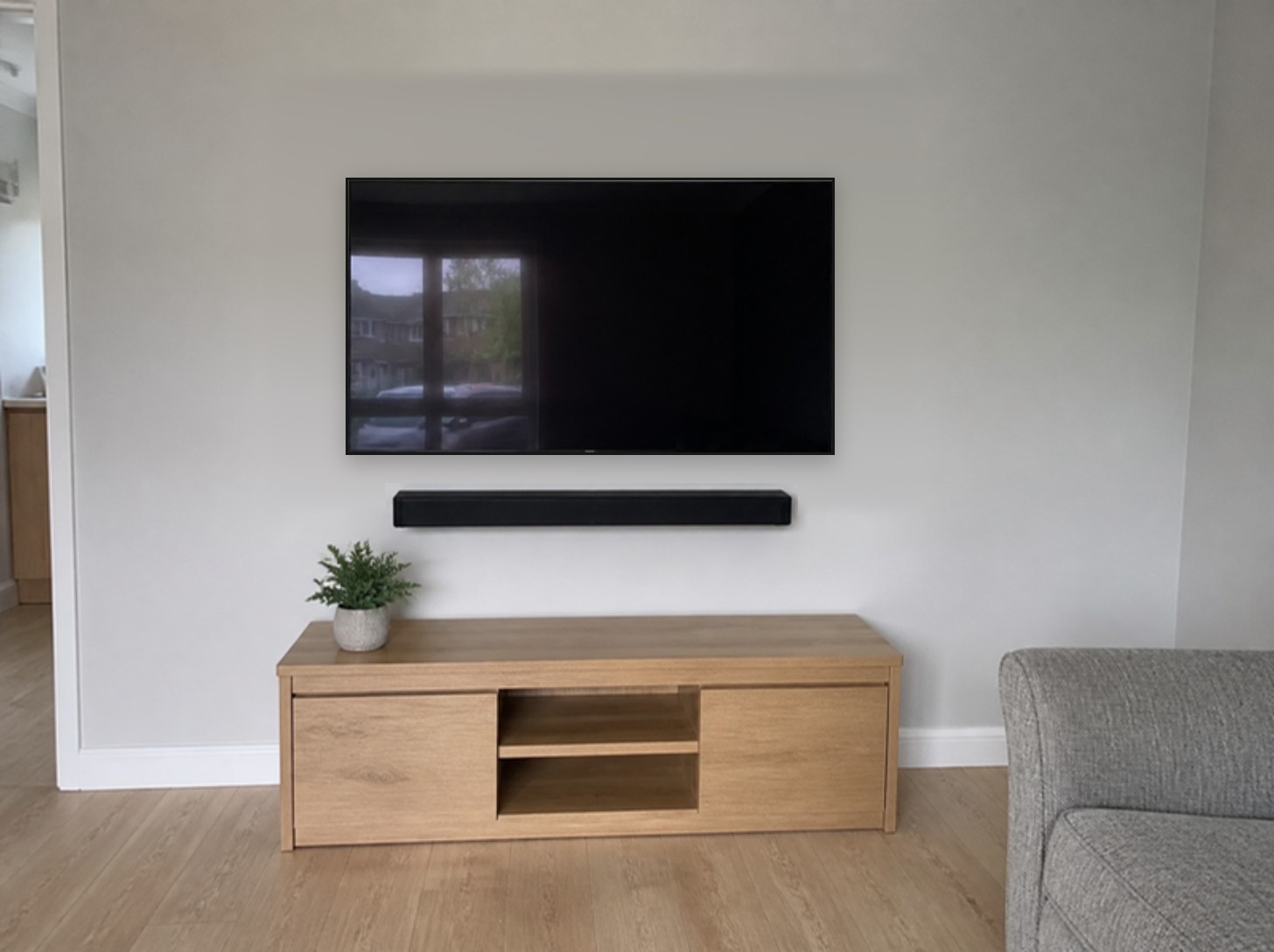 A living room TV mounted on a plain wall with no cables showing and a soundbar beneath it